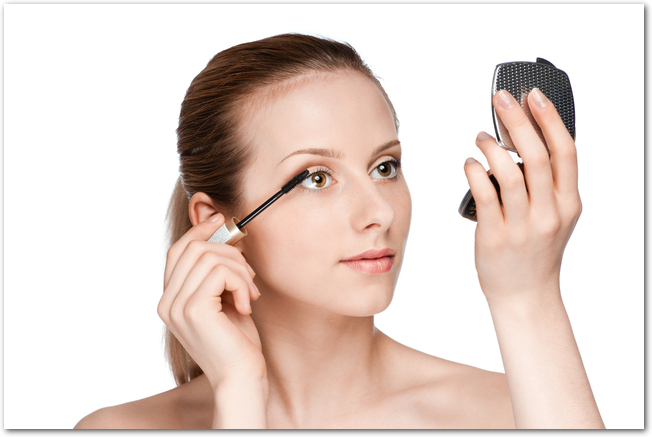 Beautiful woman applying mascara on her eyelashes