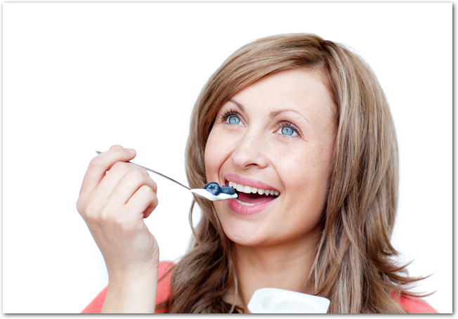 Cute woman eating a yogurt