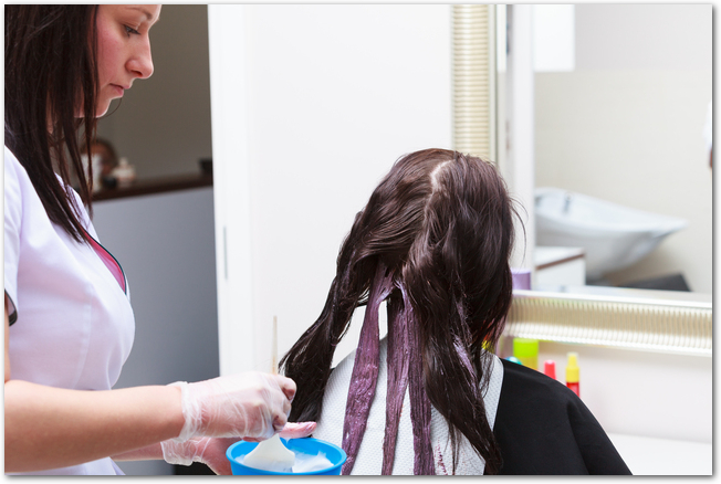 hairdresser applying color female customer at salon, doing hair dye